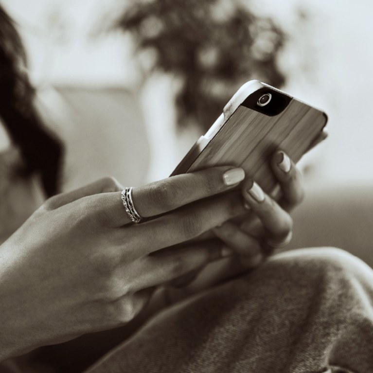 person sitting on sofa scrolling on their smartphone