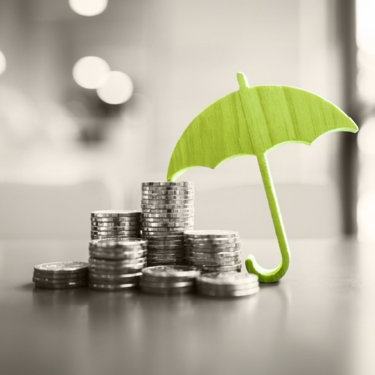 green umbrella over coins that are stacked in rising order