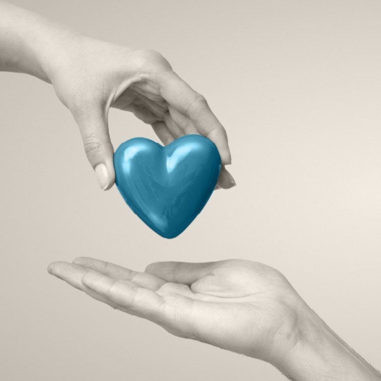 hand giving a blue teal heart to another hand