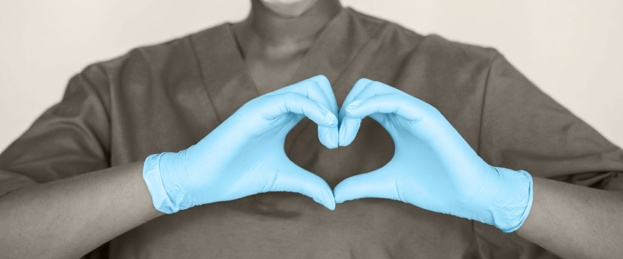nurse with blue gloves forming a heart with their hands